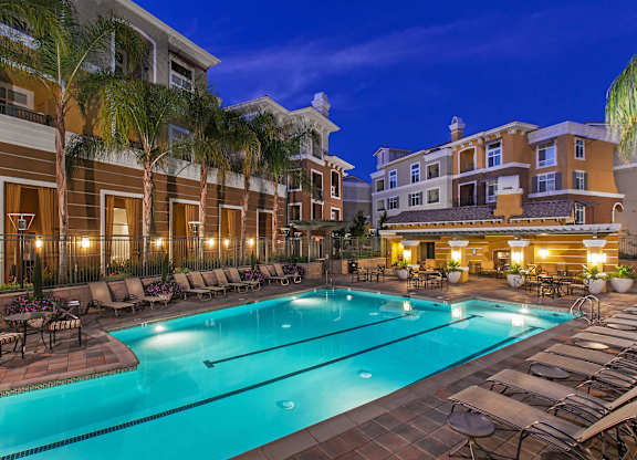 A swimming pool surrounded by lounge chairs and palm trees.