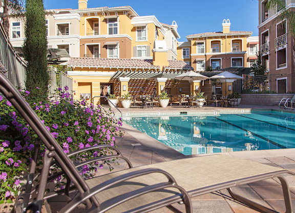 A pool surrounded by chairs and buildings.