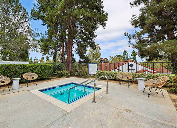 A pool surrounded by trees and chairs.