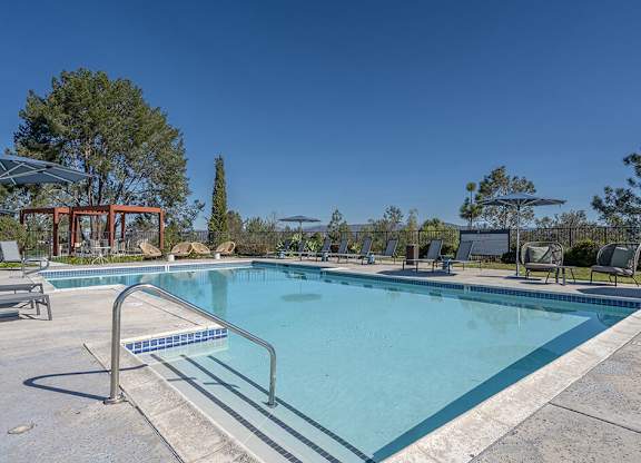 A large swimming pool with a metal ladder and a red structure in the background.