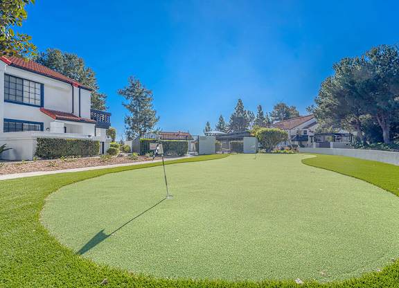 A golf course with a green and a flag on the tee.