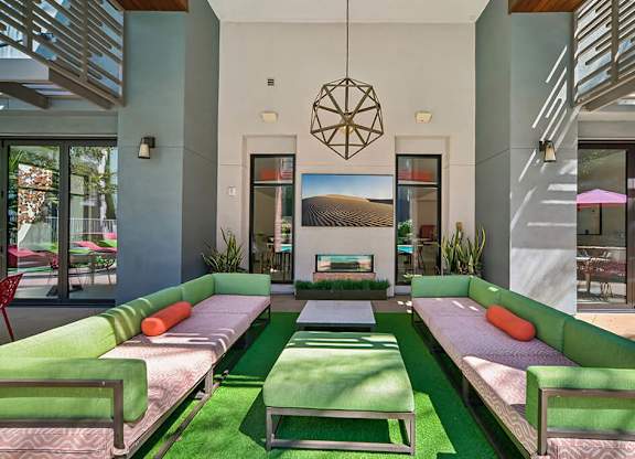 A modern living room with a green sofa and a hanging geometric light fixture.
