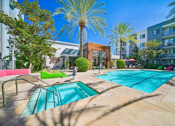A pool area with a palm tree and a building in the background.