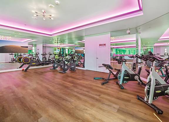 A gym with exercise bikes and a mirrored wall.