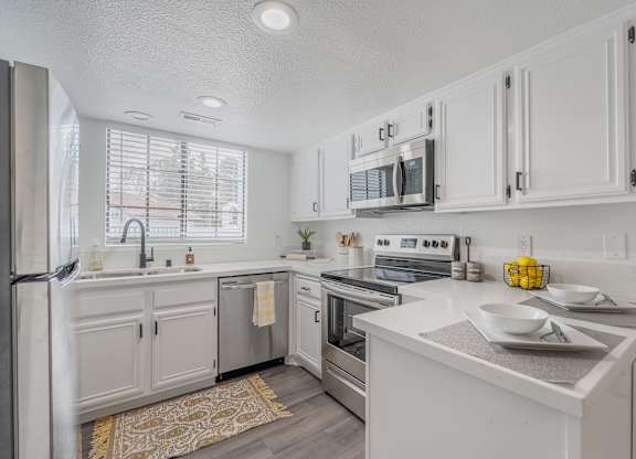 A modern kitchen with white cabinets and stainless steel appliances.