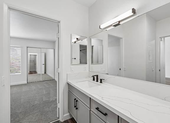 A bathroom with a sink, mirror, and a large mirror above the sink.