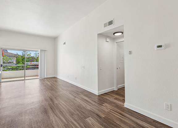 A room with a sliding glass door leading to a balcony.