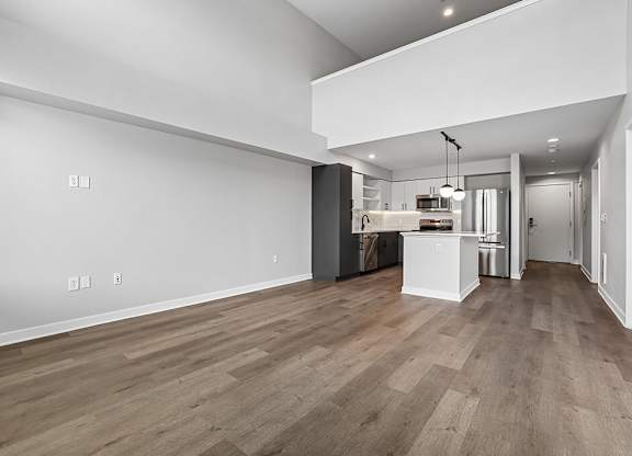 A kitchen area with a white wall and wooden flooring.