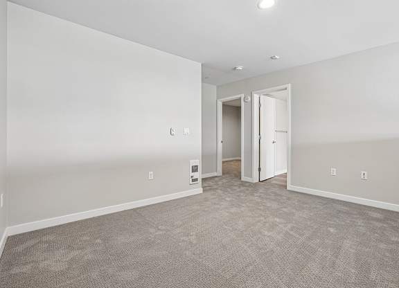 A room with a carpeted floor and a doorway leading to another room.