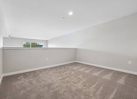 A room with a carpeted floor and a window showing a view of trees and a building.
