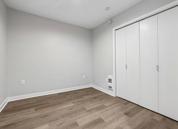 A room with a white door and wooden flooring.