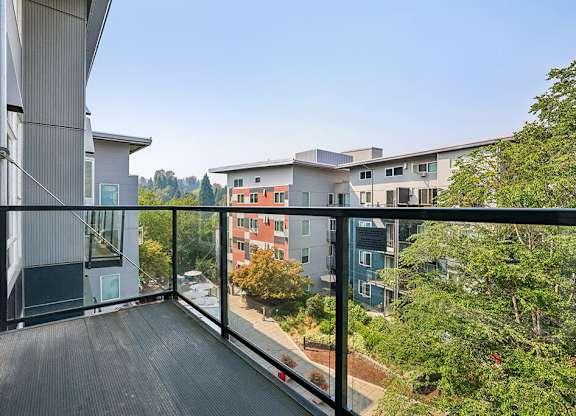 A balcony with a black railing overlooks a cityscape.