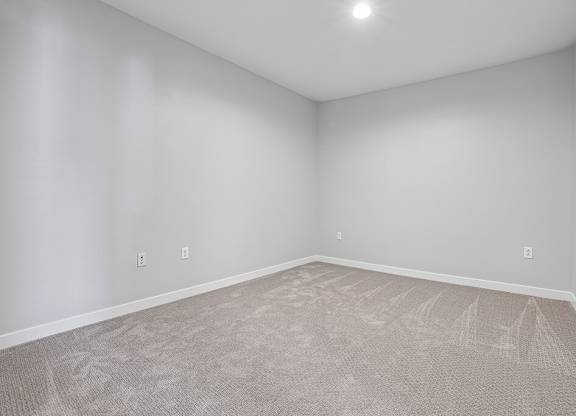 A room with a carpeted floor and two switches on the wall.