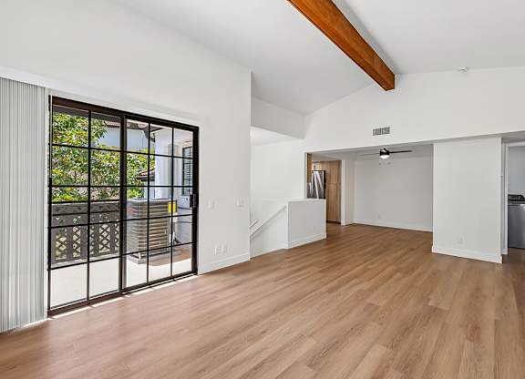 A spacious room with wooden floors and white walls.