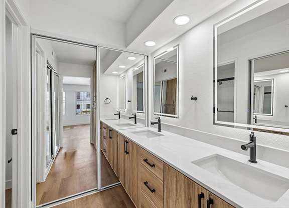 A bathroom with a white counter top and a large mirror.