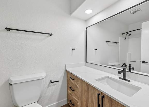 A white bathroom with a toilet, sink, and mirror.