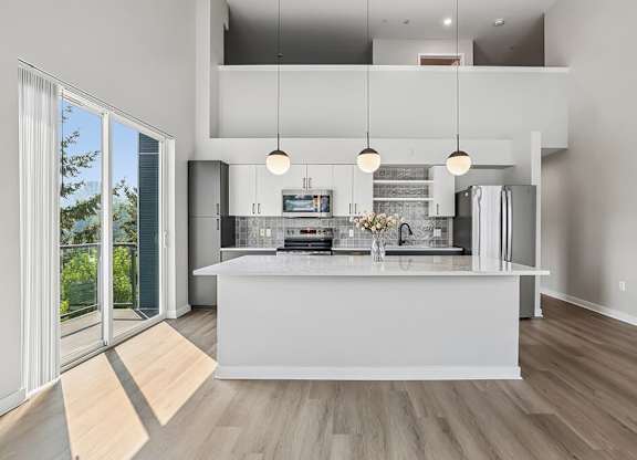 A modern kitchen with a large island and pendant lights.