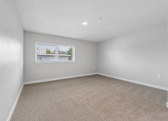 A room with a carpeted floor and a window showing a view of a house.