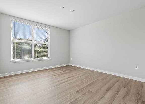 A room with a window and wooden flooring.