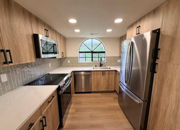 A kitchen with wooden cabinets and a stainless steel refrigerator.