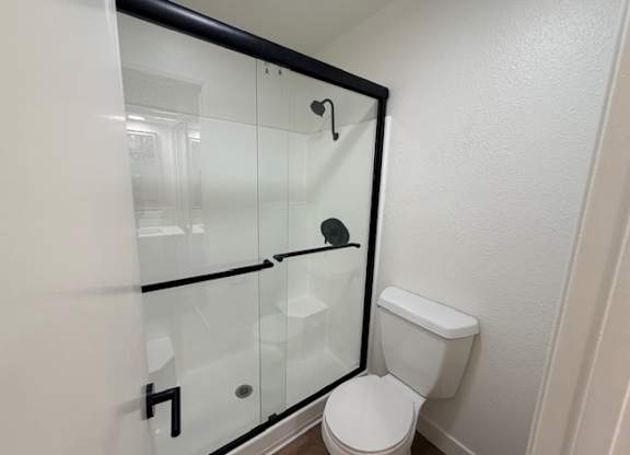 A white toilet sits next to a glass shower stall.