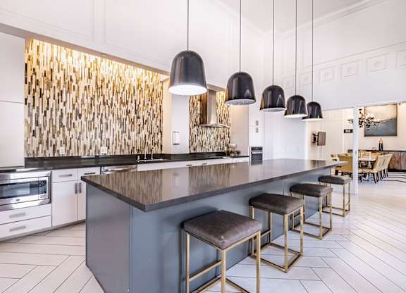 A modern kitchen with a dark countertop and bar stools.