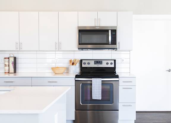 A modern kitchen with a black oven and white cabinets.