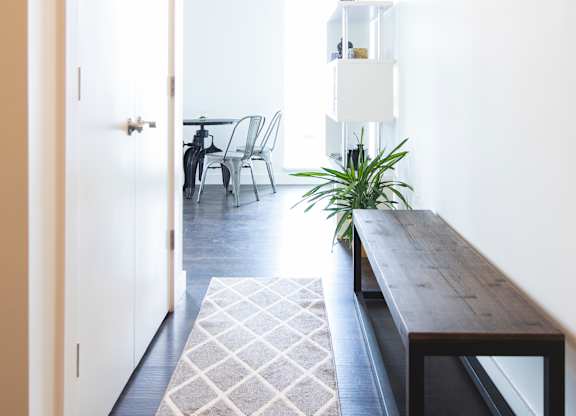 A long hallway with a bench and a rug.