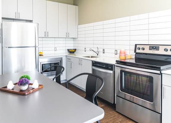 A modern kitchen with a refrigerator, oven, and microwave.