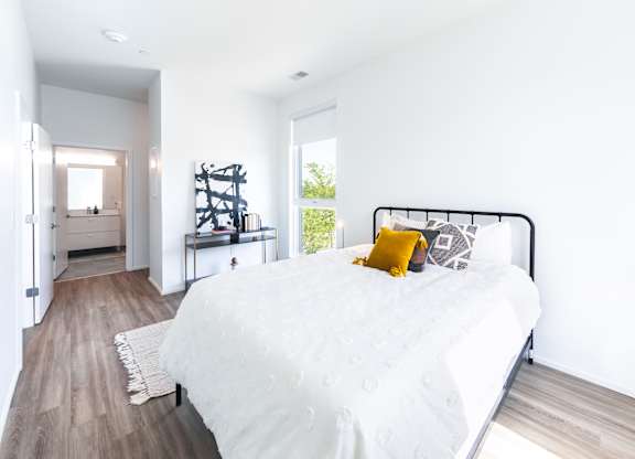 A bedroom with a white bed and a yellow pillow.
