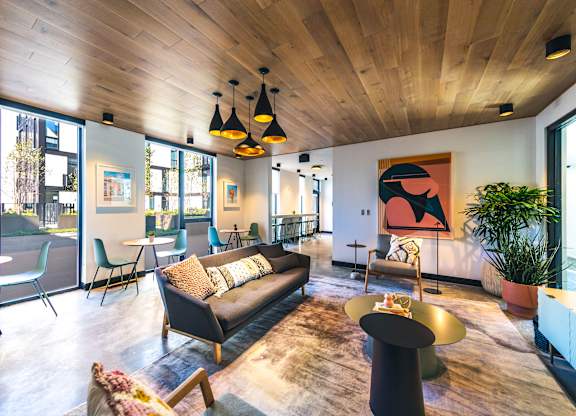 A living room with a black couch and a wooden ceiling.