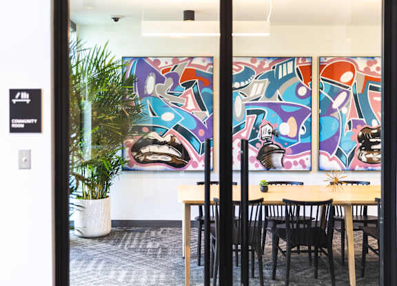 A room with a table and chairs and a painting on the wall.