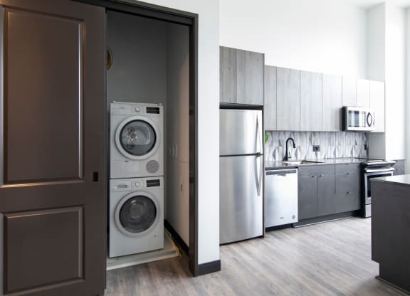 Fully equipped kitchen with stainless steel appliances includes frost-free refrigerator, electric range stove, and dishwasher, at The May.