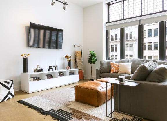 a living room with a large window and a tv on the wall at The Ferguson Apartments, Detroit, 48226