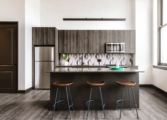 Gourmet kitchen with island, modern appliances, and elegant backsplash at The May.