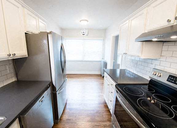 A kitchen with a black stove top oven and a black counter top.