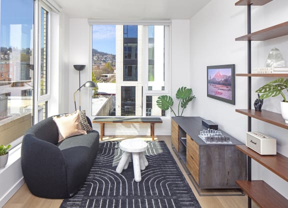 a living room with a black couch and a black and white rug and a window at The Weidler in Portland, OR 97209
