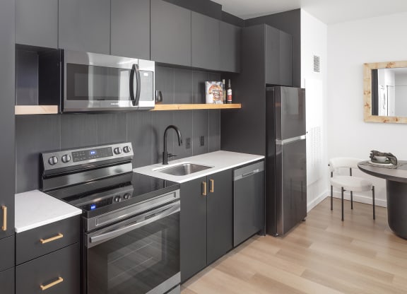 a kitchen with black cabinets and stainless steel appliances and a sink at The Weidler in Portland, OR 97209