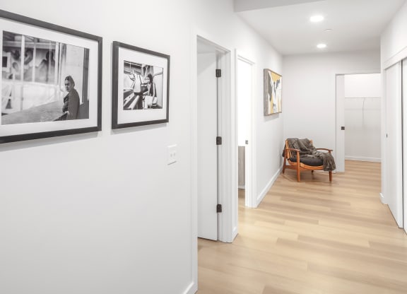 a hallway with pictures on the wall and a door to a living room at The Weidler in Portland, OR 97209