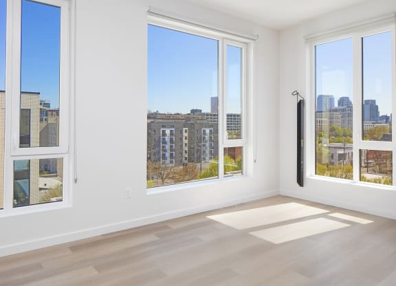 a living room with three windows and a view of the city at The Weidler in Portland, OR 97209
