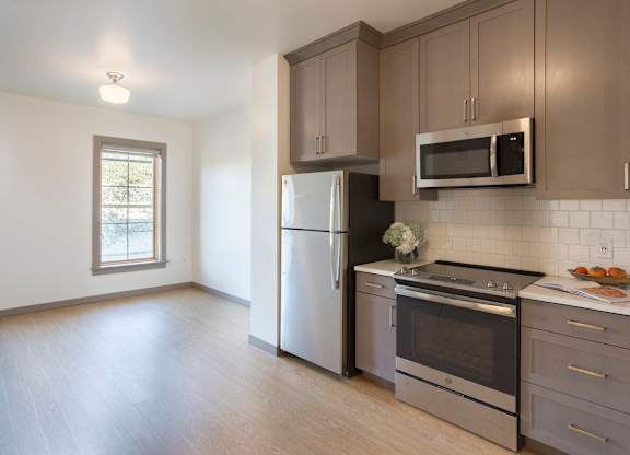 A kitchen with a refrigerator, oven, and microwave.