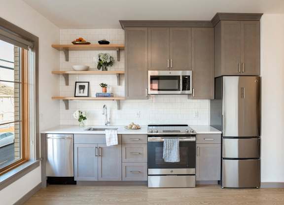 A modern kitchen with a stainless steel refrigerator, oven, and microwave.