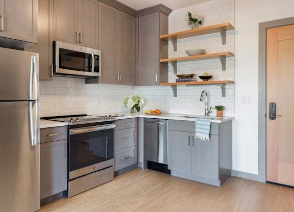 A kitchen with a refrigerator, microwave, oven, and sink.