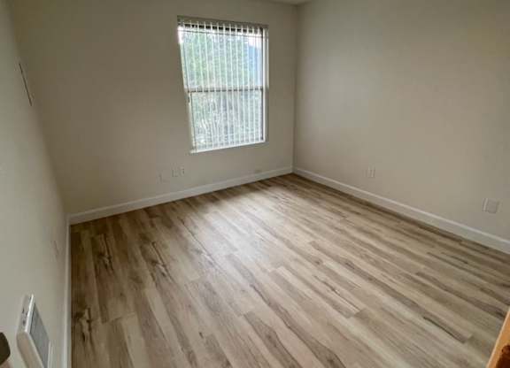 an empty room with hardwood floors and a window