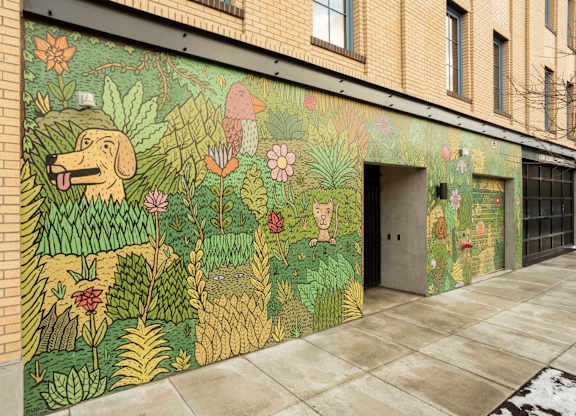 A mural of a dog surrounded by flowers and plants on a building.