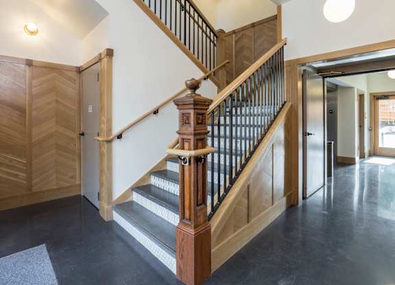 A wooden staircase with a black metal railing.
