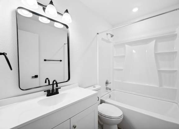 A white bathroom with a sink, toilet, and bathtub.