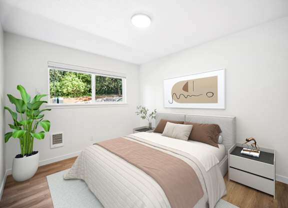 A bedroom with a large bed, a potted plant, and a framed picture on the wall.