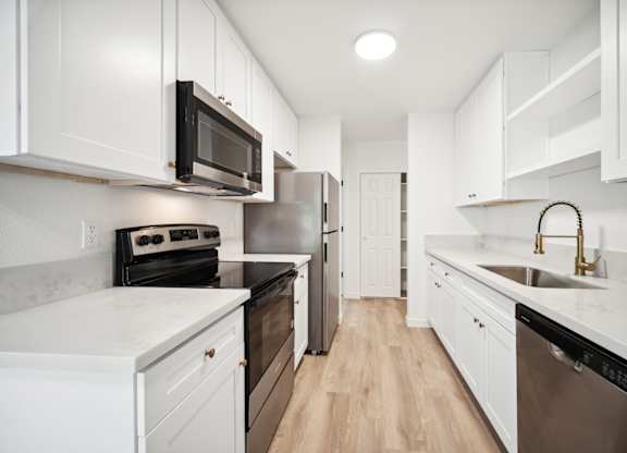 A kitchen with white cabinets and a black microwave.