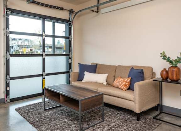 A living room with a couch, coffee table, and a plant.